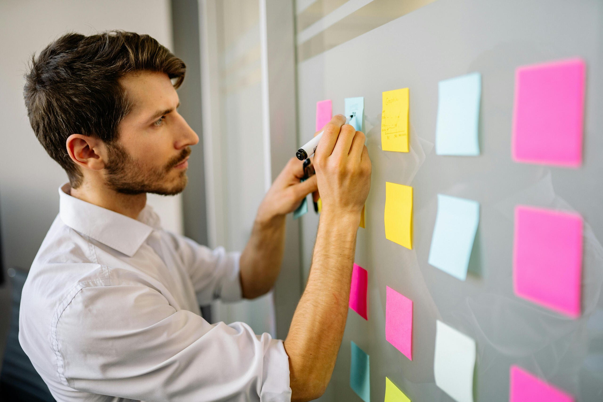 Technology frustration and digital overwhelm Professional writing on colorful sticky notes during a design planning session, symbolizing Brasstown Consulting’s focus on helping product teams create intuitive, user-centered tools